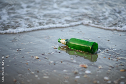 The green glass bottle waste on the beach.
