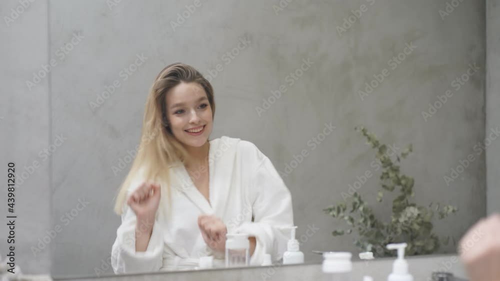 Young beautiful girl enjoys her appearance standing in the bathroom in front of the mirror, she is happy. Young beautiful girl enjoys her appearance standing in the bathroom in front of the mirror, she is happy.