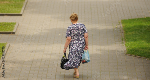 a woman with heavy bags walks along the street
