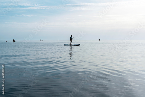 Young man floating on stand up paddle board on the sea on sunny summer day, active lifestyle, outdoor activity