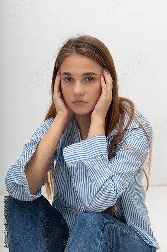 portrait of young attractive caucasian woman with long brown hair in t-shirt and blue shirt isolated on white background. skinny pretty female sitting at studio. model tests of beautiful lady