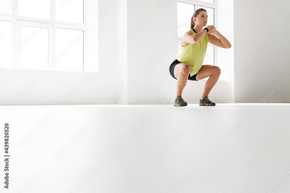 Young white sportswoman doing exercise while working out indoors Young white sportswoman doing exercise while working out indoors