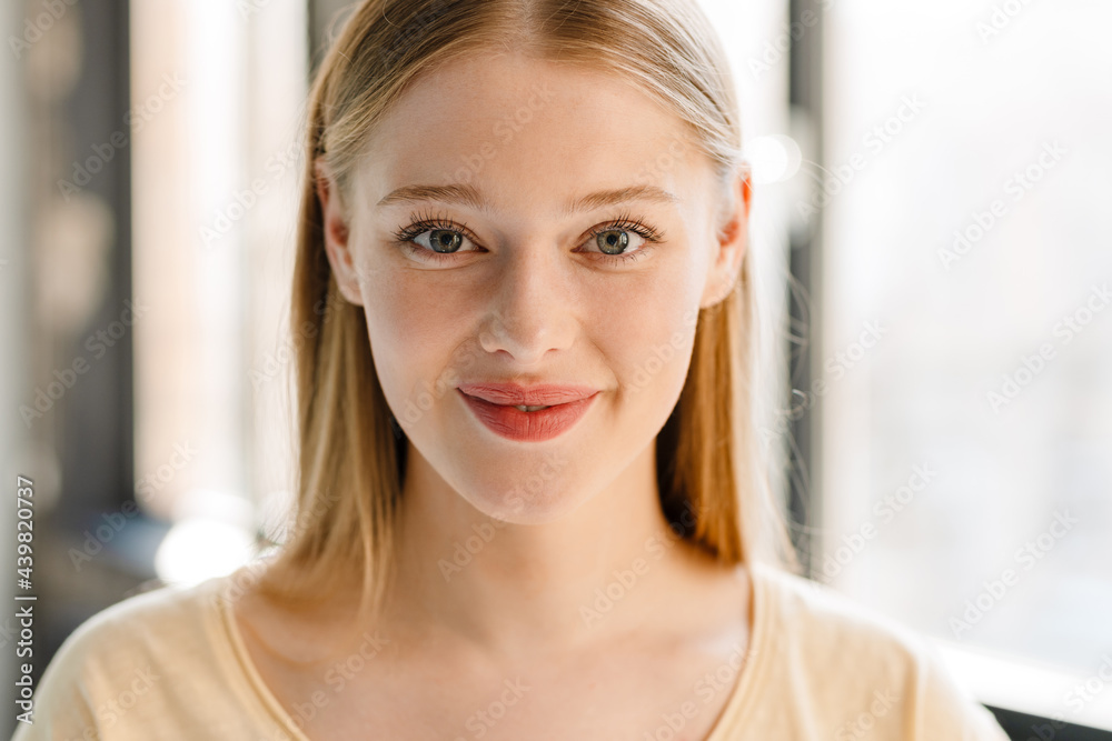 Young blonde white woman smiling and looking at camera indoors Young blonde white woman smiling and looking at camera indoors