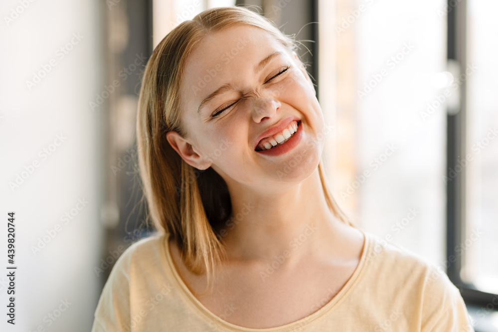 Young blonde white woman laughing while posing at camera indoors