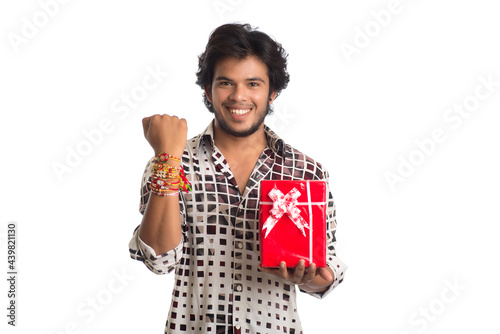 Man or Brother showing rakhi on his hand with shopping bags and gift box on the occasion of Raksha Bandhan festival.