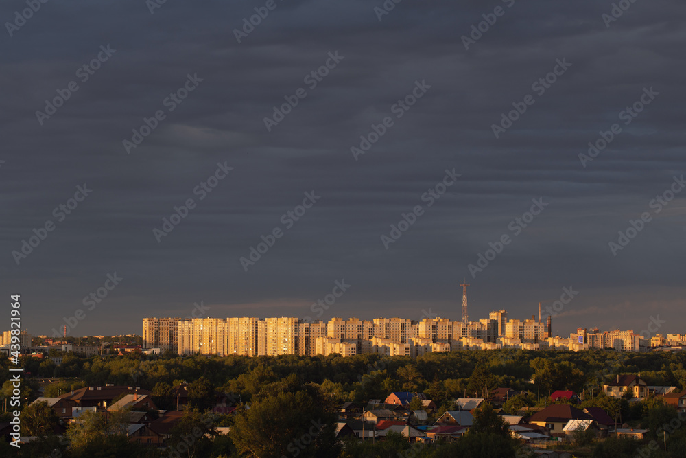 Panoramic view of city with skyline with blue sky with tall buildings and sector of cottages with trees.