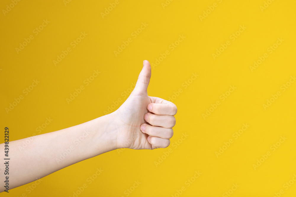 Teens hand with thumb up isolated on yellow background. Showing like, positive sign. Symbol, icon of perfect or accept.