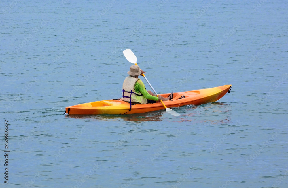 senior man canoeing on the beach at sunset