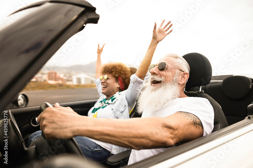 Happy senior couple having fun in convertible car during summer vacation - Focus on man face photo