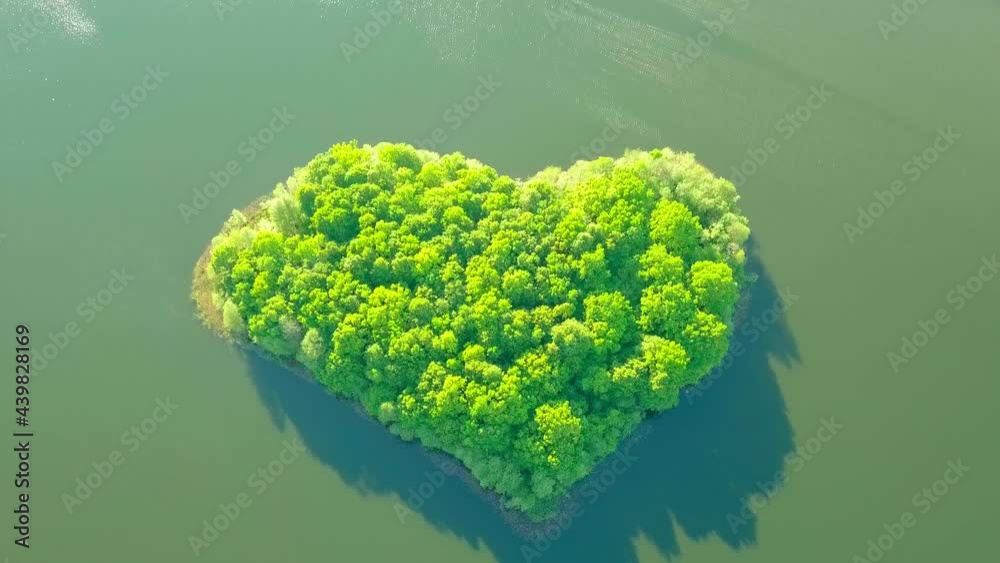 Aerial photography from drone of lake and small island in shape of heart. Unusual natural phenomena. copter takes bird's-eye view of heart-shaped island with greenery in summer on hot day at sunset. Aerial photography from drone of lake and small island in shape of heart. Unusual natural phenomena. copter takes bird's-eye view of heart-shaped island with greenery in summer on hot day at sunset.