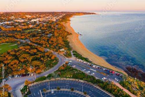 Aerial view of a bay side beach and carpark in late afternoon sunshine photo