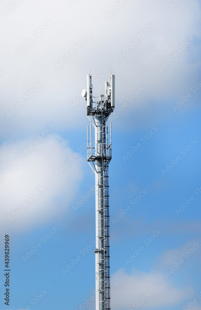 Telecommunication tower with antennas on a background of blue sky and clouds. Smart antennas transmit 4G and 5G cellular signals to consumers. Telecommunication tower with antennas on a background of blue sky and clouds. Smart antennas transmit 4G and 5G cellular signals to consumers.
