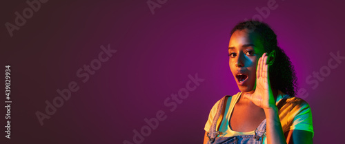 Photos Latino young woman's portrait on dark studio background in neon
