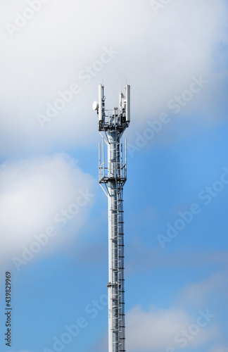 Telecommunication tower with antennas on a background of blue sky and clouds. Smart antennas transmit 4G and 5G cellular signals to consumers.