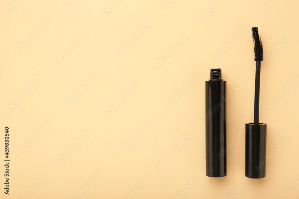 Black mascara wand and tube on beige background with copy space Black mascara wand and tube on beige background with copy space