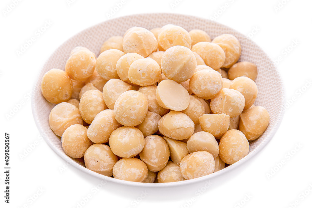 macadamia nut kernels in a white plate on a white background. Isolated items and products macadamia nut kernels in a white plate on a white background. Isolated items and products