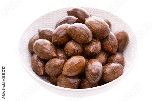 Pecans in a white plate on a white background. Isolated items and products