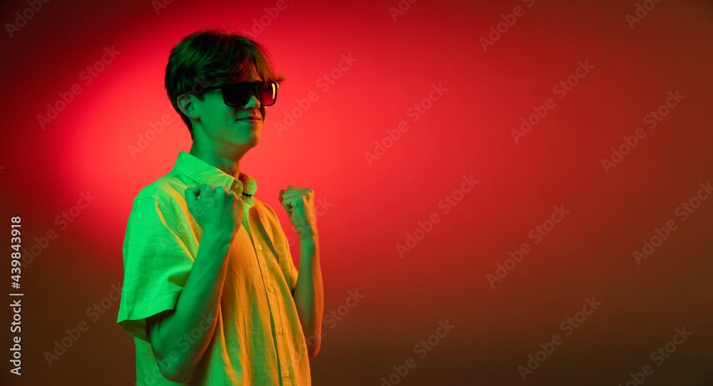Crazy happy winner. Young caucasian man's portrait on gradient blue-pink studio background in neon light. Concept of youth, human emotions, facial expression, sales, ad.