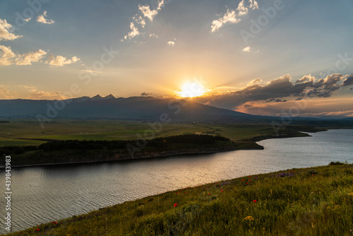 Beautiful golden sunset on the river and panoramic view on the mountains and hills.