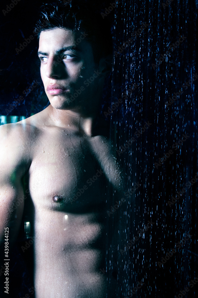 Sexy portrait of handsome naked man with beard and brown eyes under a rainfall shower looking at camera Sexy portrait of handsome naked man with beard and brown eyes under a rainfall shower looking at camera