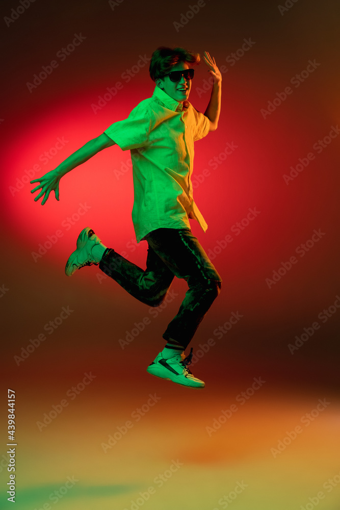 Caucasian young man in headphones isolated on blue studio background in neon. Concept of human emotions, facial expression.