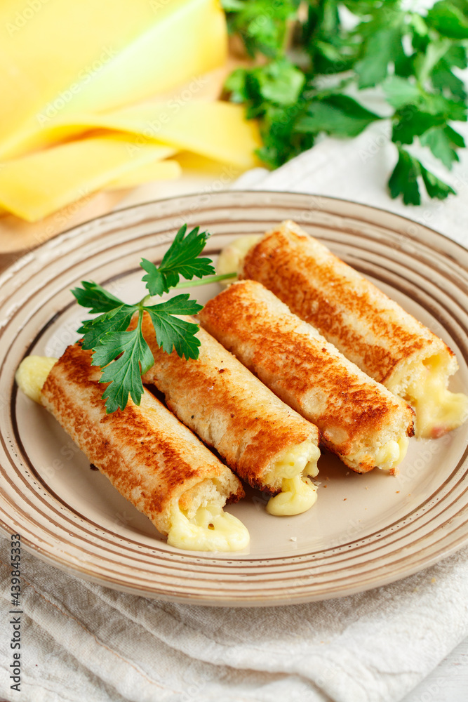 Fried rolls of bread and parmesan cheese with parsley on a plate on a white wooden background. Breakfast. Brunch. A delicious snack for gourmets. Selective Focus Fried rolls of bread and parmesan cheese with parsley on a plate on a white wooden background. Breakfast. Brunch. A delicious snack for gourmets. Selective Focus