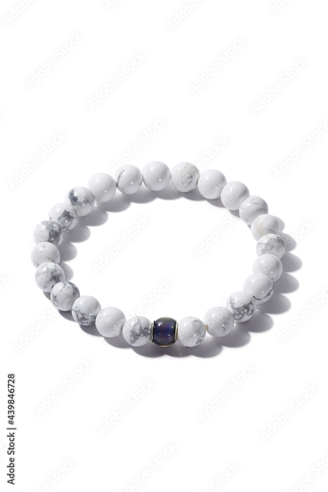 Detail shot of beaded bracelet made of white marble and decorated with blue cat eye bead. Stylish bracelet is isolated on the white background. Detail shot of beaded bracelet made of white marble and decorated with blue cat eye bead. Stylish bracelet is isolated on the white background.