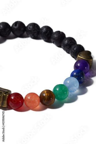 Cropped shot of beaded bracelet made of lava rock, colorful ornamental stones and decorated with golden heart and animal paw. Stylish bracelet is isolated on the white background. 