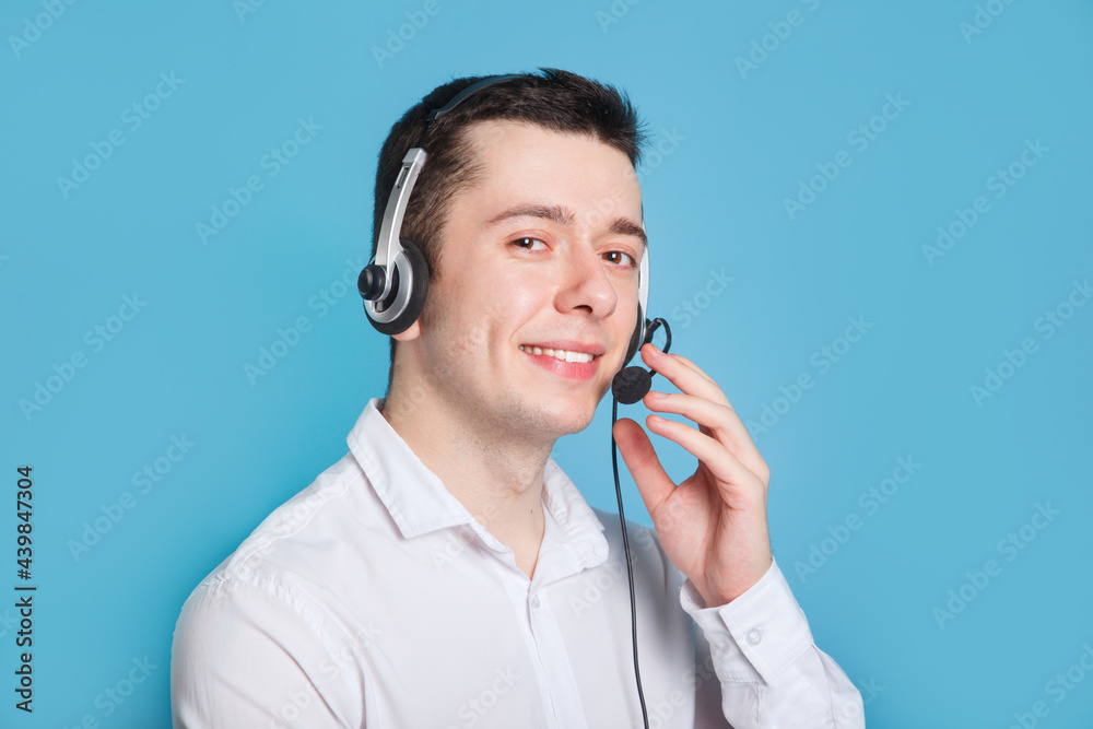 Smiling call center operator on blue background. Headset touching.