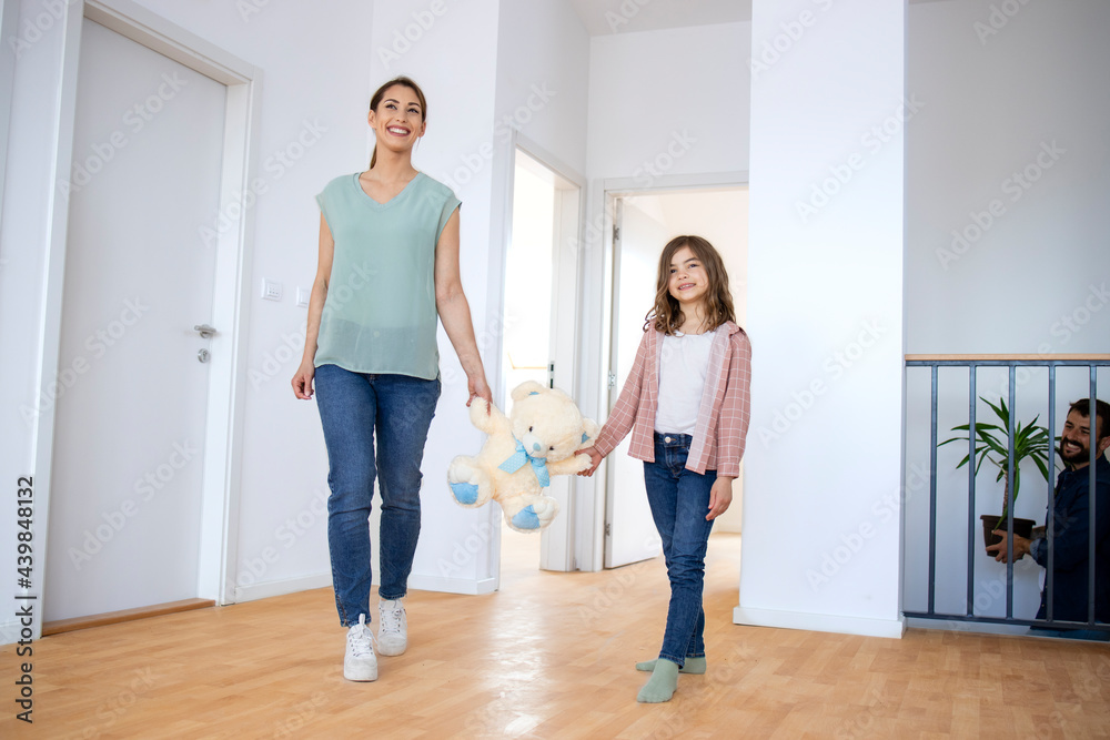 Mother and daughter holding teddy bear toy and entering their new house. Mother and daughter holding teddy bear toy and entering their new house.