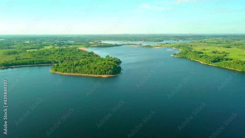 Flying over a taiga forest lake. The drone flies over a picturesque place, a large lake surrounded by forest and greenery in spring on a sunny summer day. Belarus, Braslav lakes.