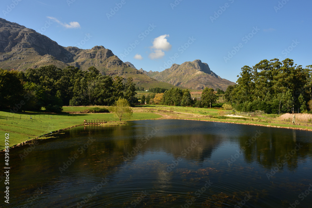 A huge pond against a scenic mountain and blue sky backdrop in the Western Cape in South Africa