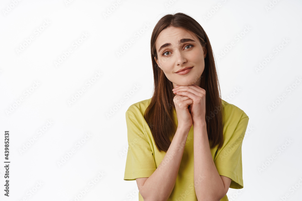 Portrait of young silly girl making adorable face, lean on hands and asking for smth, begging, contemplating beautiful thing, standing over white background Portrait of young silly girl making adorable face, lean on hands and asking for smth, begging, contemplating beautiful thing, standing over white background