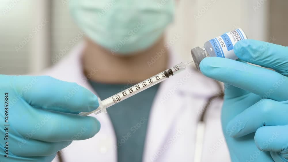 Close up of Doctor in face mask holds syringe and bottle with vaccine for covid 19 in hospital. Medical hands filling syringe with vaccine for corona virus cure. Vaccination and immunization concept. Close up of Doctor in face mask holds syringe and bottle with vaccine for covid 19 in hospital. Medical hands filling syringe with vaccine for corona virus cure. Vaccination and immunization concept.