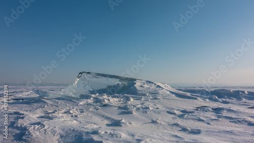 A large ice floe rises on a frozen lake. Transparent ice against the blue sky. Snowdrifts around. Sunny winter day. Baikal © Вера 