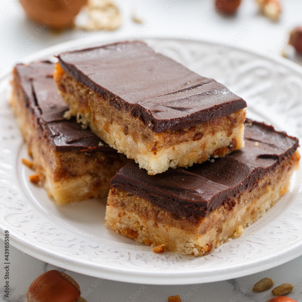 Homemade Vegan cocoa dates chocolate bars with coconut, hazelnuts, walnuts and sunflower seeds on a white background. Healthy dessert. The concept of plant food. Shallow depth of field Homemade Vegan cocoa dates chocolate bars with coconut, hazelnuts, walnuts and sunflower seeds on a white background. Healthy dessert. The concept of plant food. Shallow depth of field