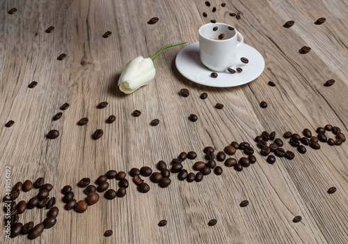 Coffee beans form the words  buongiorno   good morning in Italian  with a cup of espresso on which other beans fall