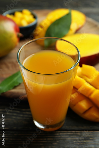 Ripe mango fruit and juice on wooden table