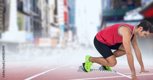 Caucasian male athlete in starting position to run on sports field against city streets
