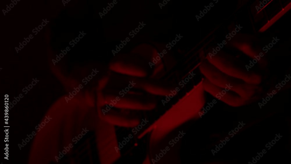 Guitarist playing tapping in low concert lighting Guitarist playing tapping in low concert lighting