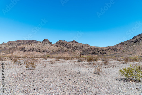 Barren desert valley with barren mountains under a clear blue sky © John