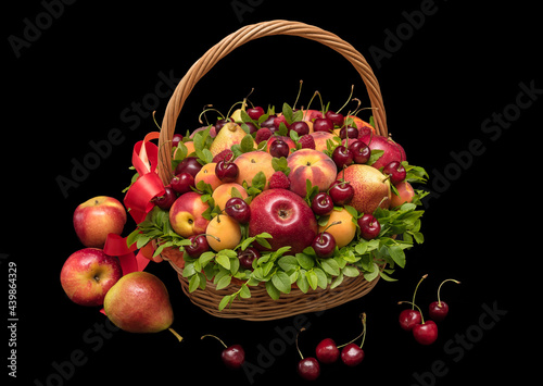 Basket with fresh fruits and berries on a black background close up