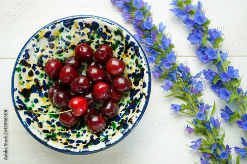 fresh ripe cherries in a bowl on white wooden background