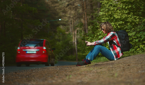 Male tourist sitting near the road with mobile phone. © M-Production