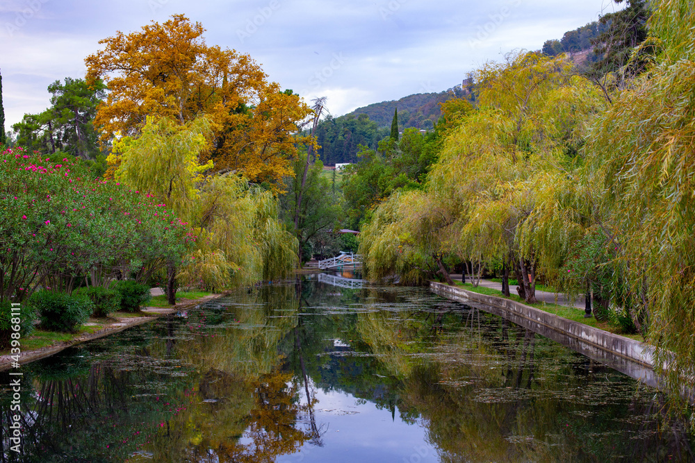 River channel in the park in the fall in the distance a beautiful bridge over it River channel in the park in the fall in the distance a beautiful bridge over it