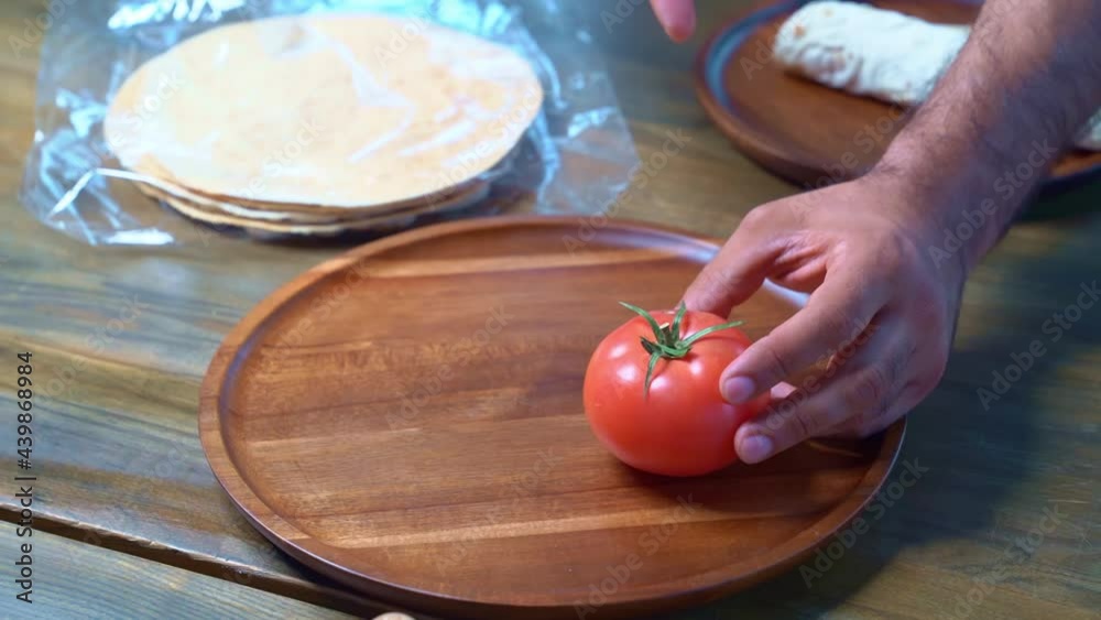 men's hands beautifully spread tomatoes on a wooden round cutting board. men's hands beautifully spread tomatoes on a wooden round cutting board.