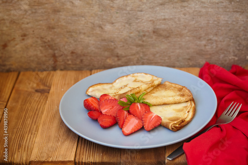 Pancakes  thin pancakes with fresh strawberries. On a wooden background. Copy space.