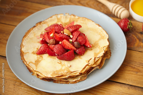 Pancakes  thin pancakes with fresh strawberries. On a wooden background. Copy space.