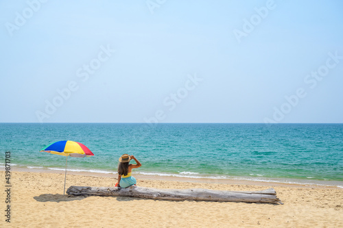 Sexy woman sitting on the beach with colorful umbrella at Mai Khao Beach, Phuket, Thailand