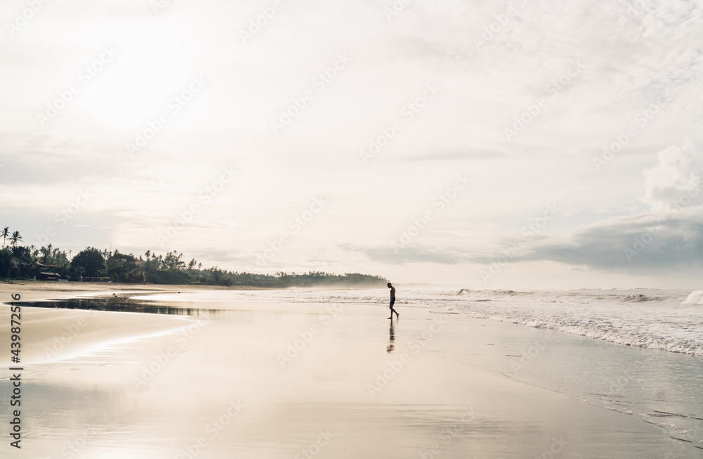 Anonymous man walking on sandy beach